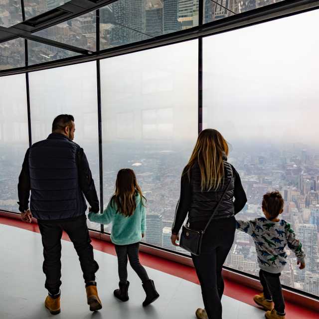 A family looks out at the Toronto city skyline from the observation deck at the CN Tower.