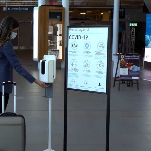 A person using the hand sanitizer station at Billy Bishop Airport