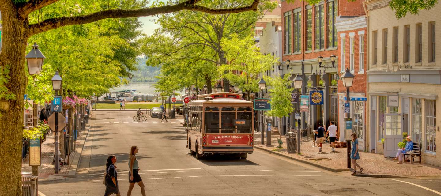 Pedestrians walking and a trolley passing through Downtown Alexandria, VA