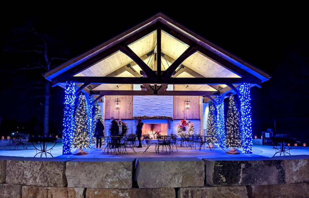 A pavilion complete with Fireplace is lined with blue and white lights at Botanica Illuminations 