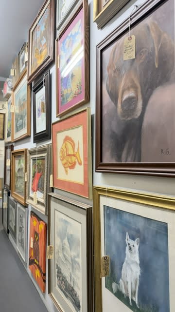 A hallway is lined with a variety of vintage prints and frames.