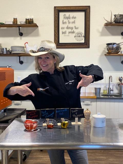 Owner Dawn in Cowboy Hat pointing to different cooking ingredients
