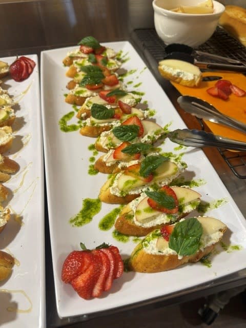 A tray of bread with cheese, strawberries and basil