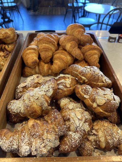 Assorted croissants and almond pastries dusted with powdered sugar displayed in wooden trays at L’Etoile Patisserie in Huntsville.
