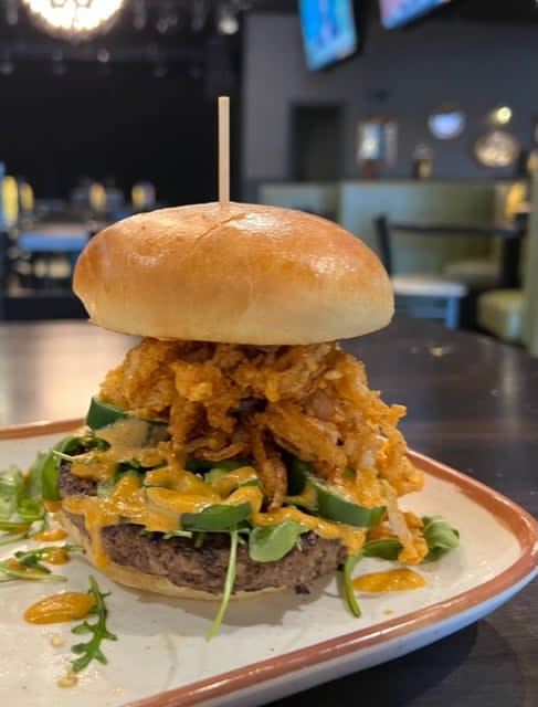 Burger heaped with cheese and fried onions at the Blind Squirrel in Florence, Ky.