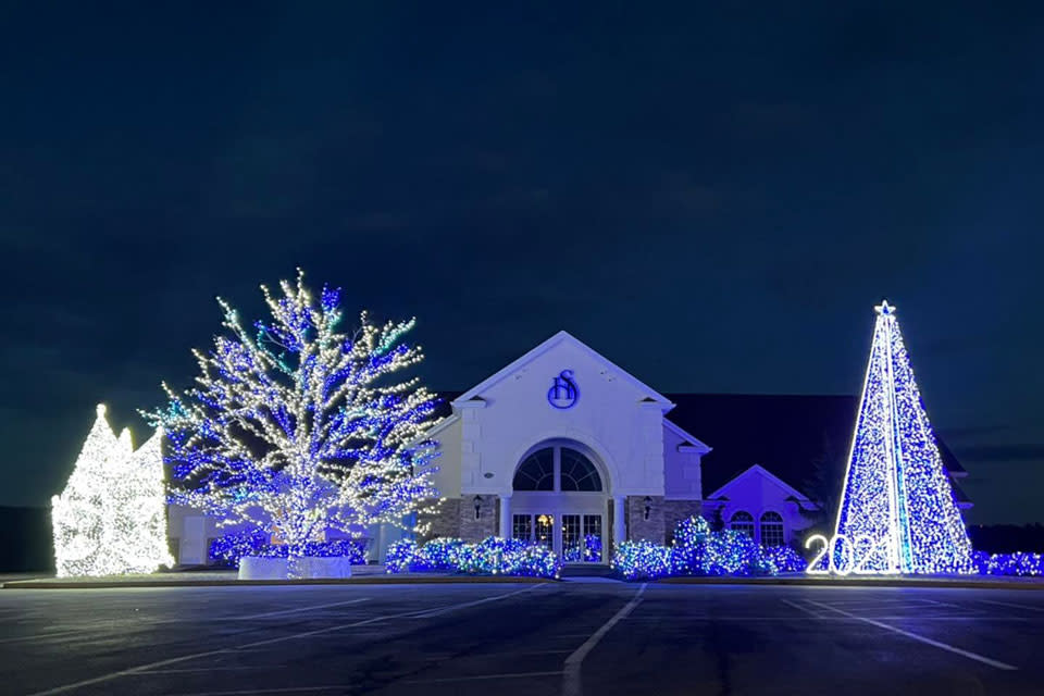 a large Christmas Tree with Lights in front of Church
