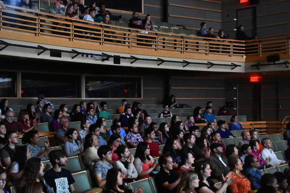 audience sitting in chairs inside theater