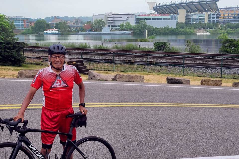 A senior person standing next to cycle with gear on