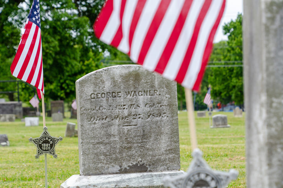A tombstone with a flag in the background