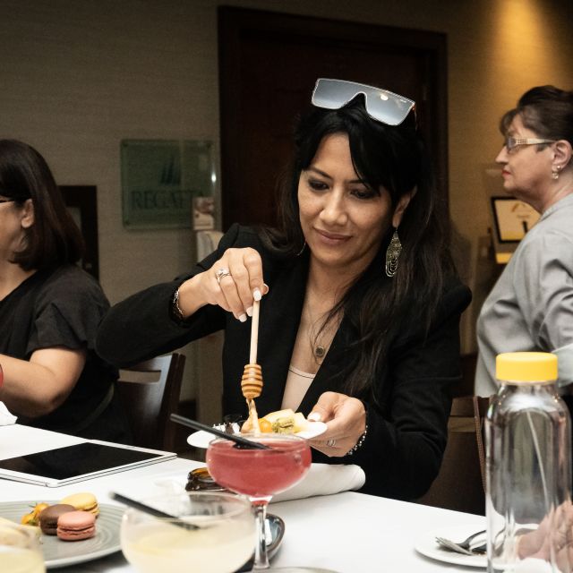 Woman pouring honey in a food plate with two other women around her