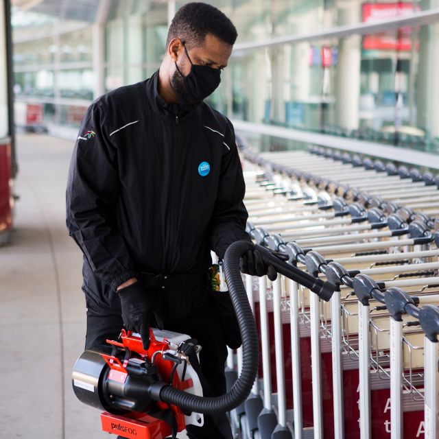 A staff member at Toronto Pearson disinfects baggage carts with a disinfecting fogging machine