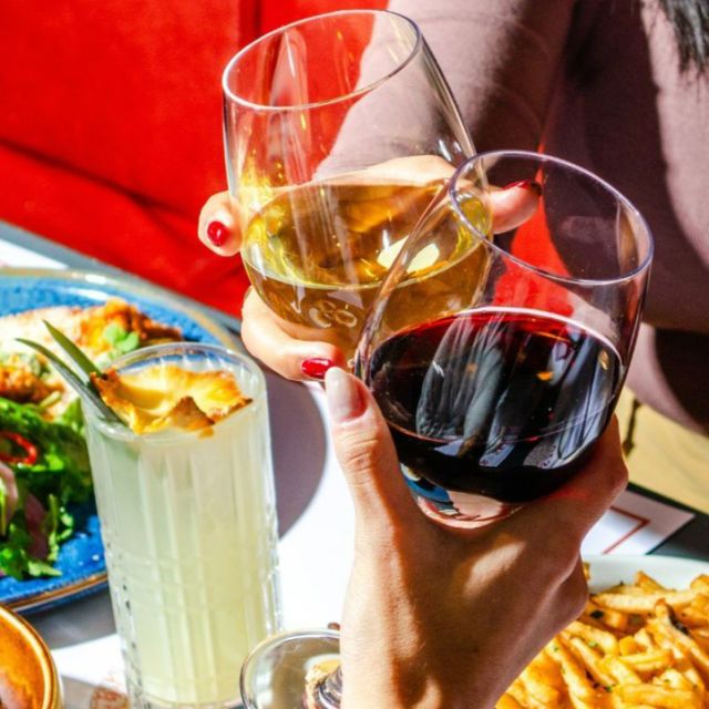 Two people clinking wine glasses together at dinner
