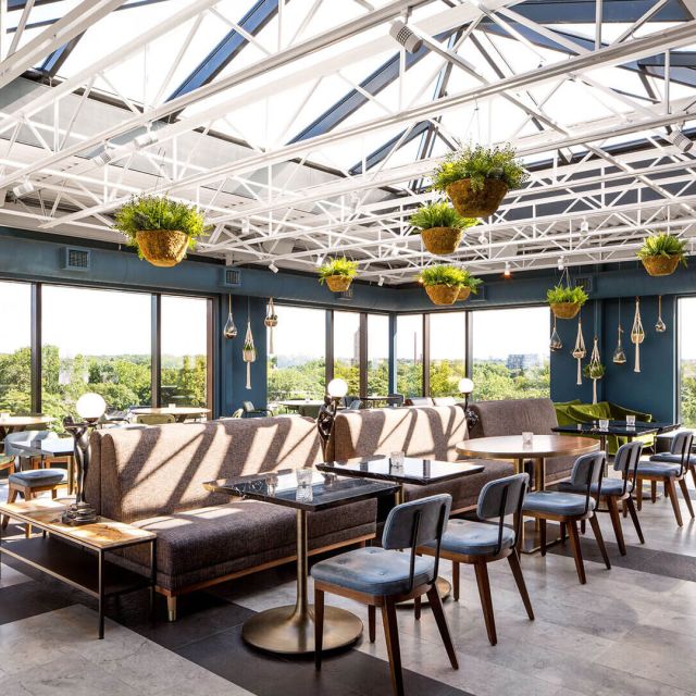 The Broadview Rooftop at daytime, interior shot with tables chairs and hanging plants