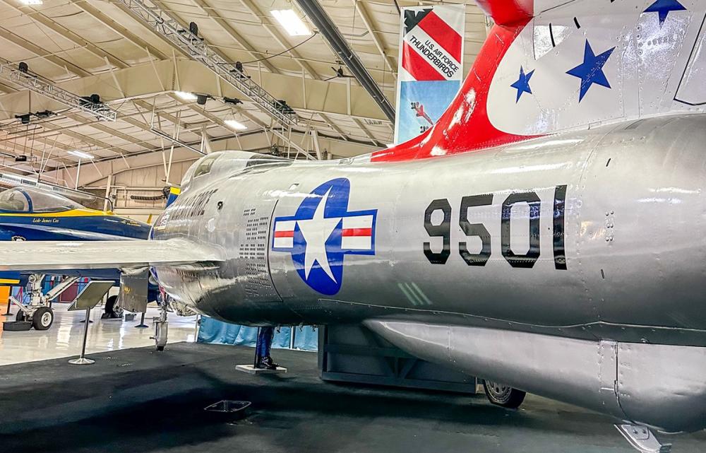 silver plane with stars and number "9501" painted on side sits inside a museum.