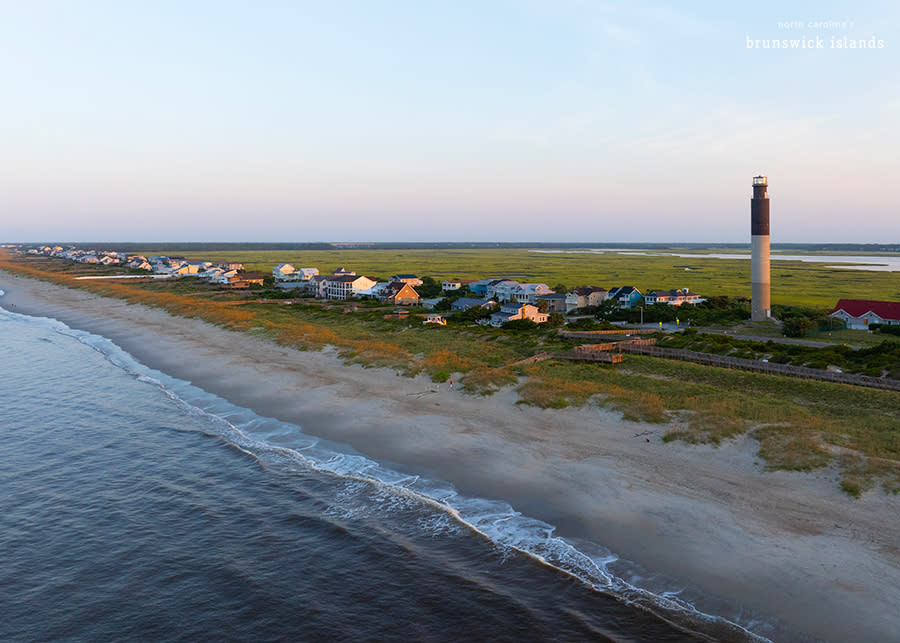 an aerial view of caswell beach and the oak island lighthouse