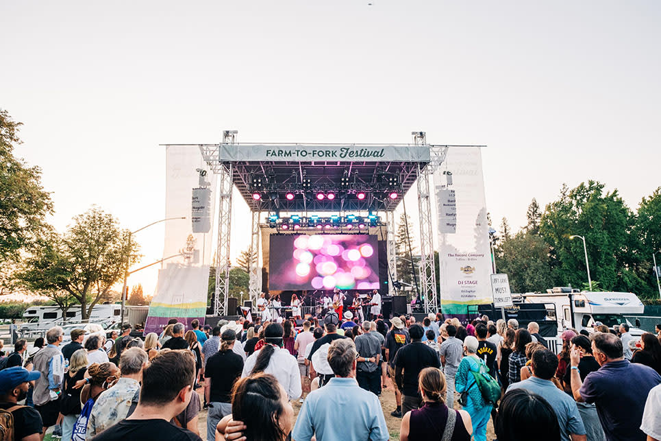 crowd standing in front of an outdoor music stage at the farm to fork festival