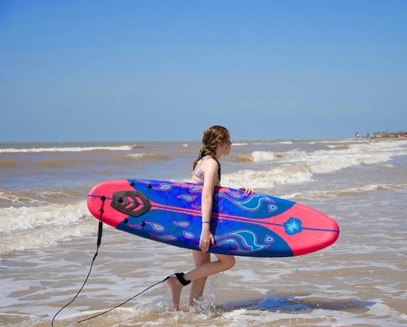 Una señora con una tabla de surf en Surfside Beach.