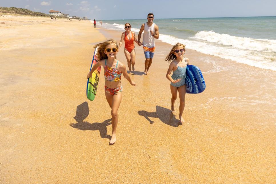 A family runs on the beach.