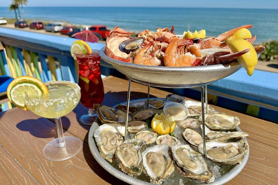 A seafood platter on a table with the ocean in the background.