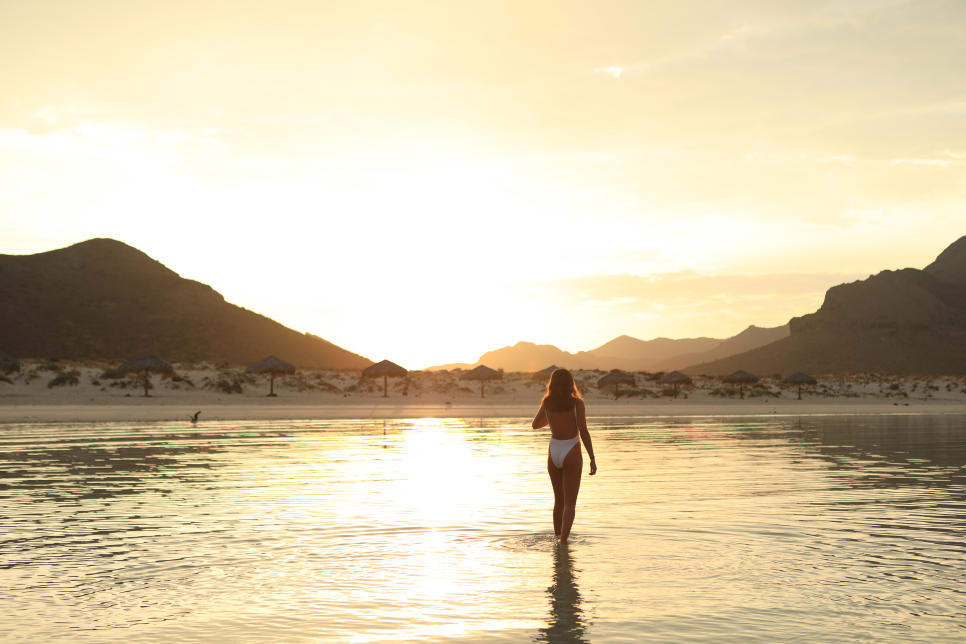 Mujer caminando al atardecer en playa en Los Cabos