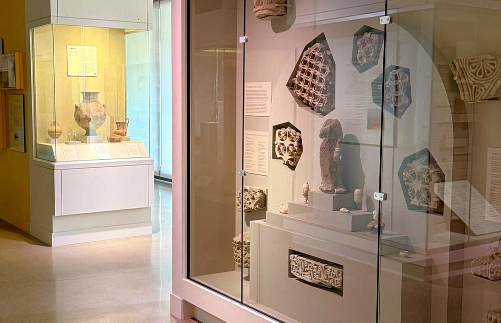 Glass cases are filled with historic artifacts in a dimly lit display inside of a museum.