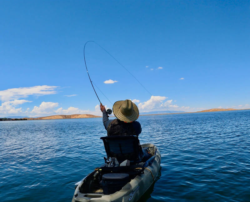 A man sits in a kayak while fly fishing on a lake in New Mexico