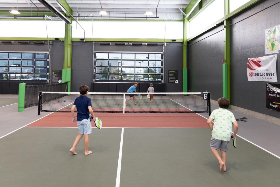 Barefoot boys play indoor pickleball at Chicken N Pickle in Wichita, KS.