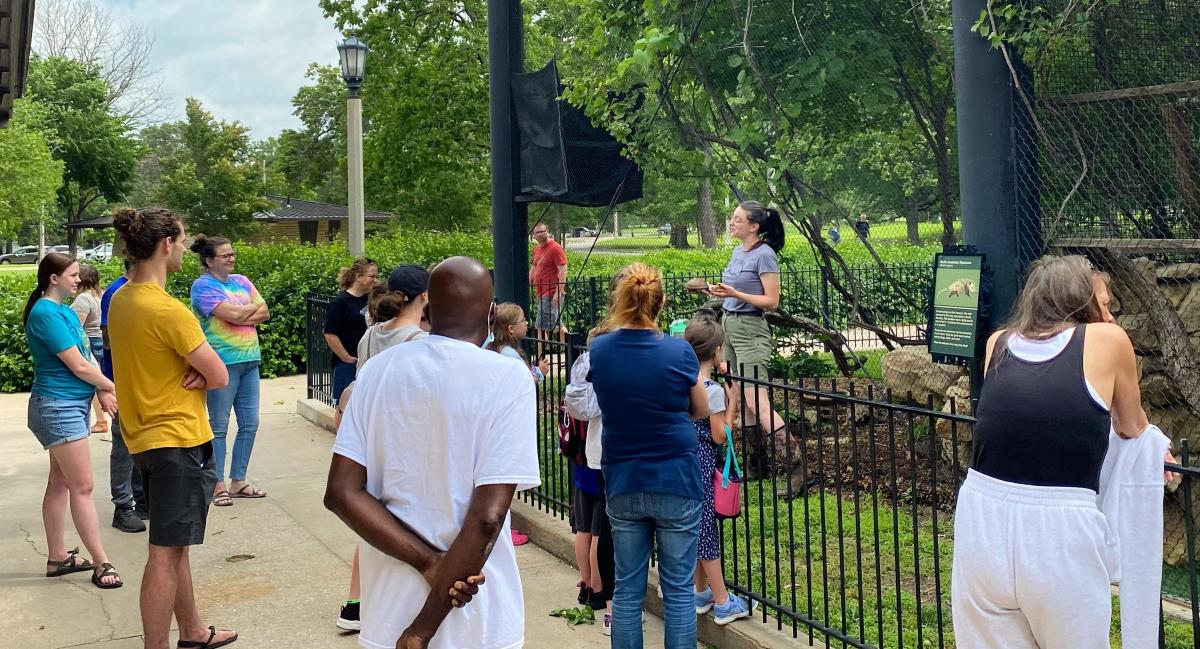 People gather to hear a zookeeper as they talk about an animal outside an enclosure at the Kansas Wildlife Exhibit.