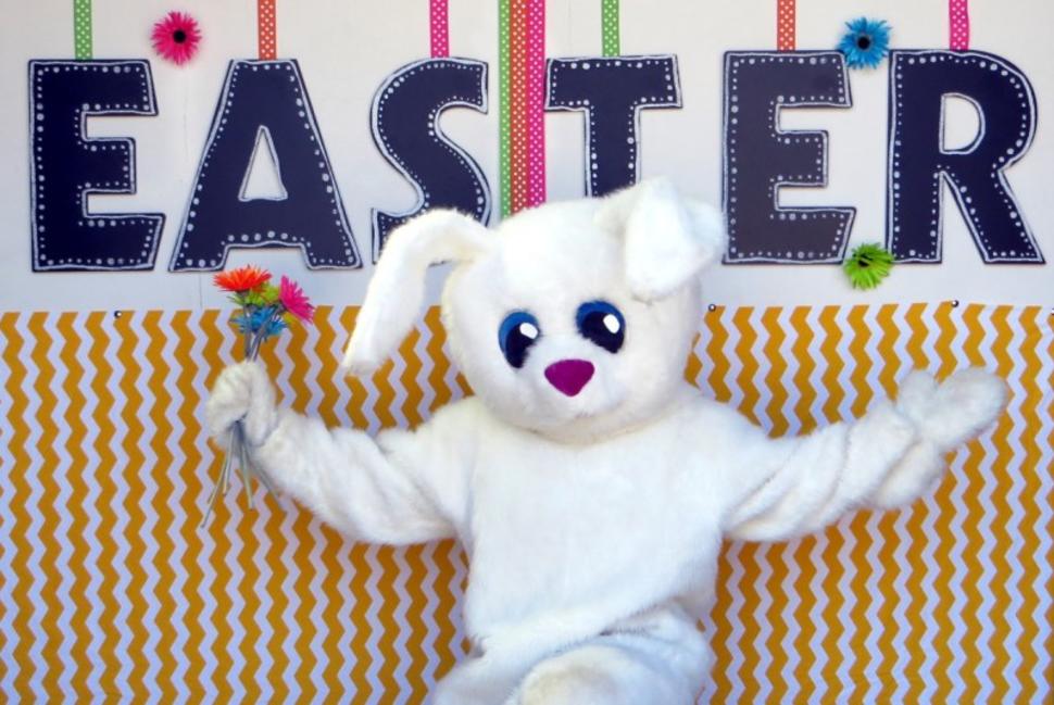 Easter bunny stands under a sign that says "Easter"