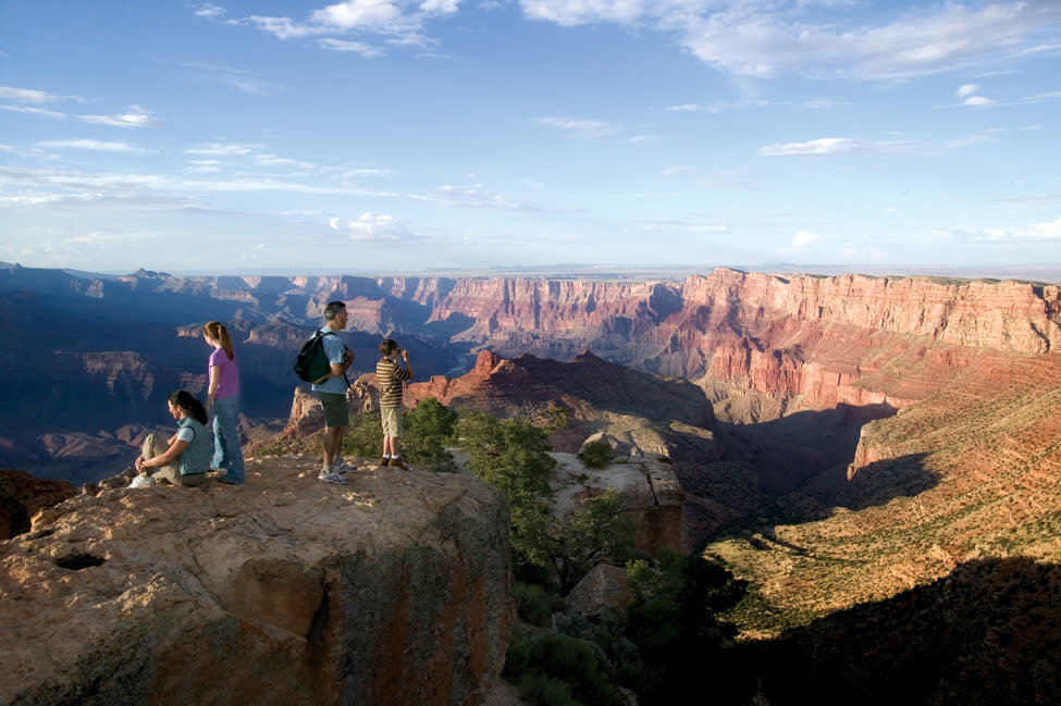 Family of four standing looking out into the Grand Canyon.