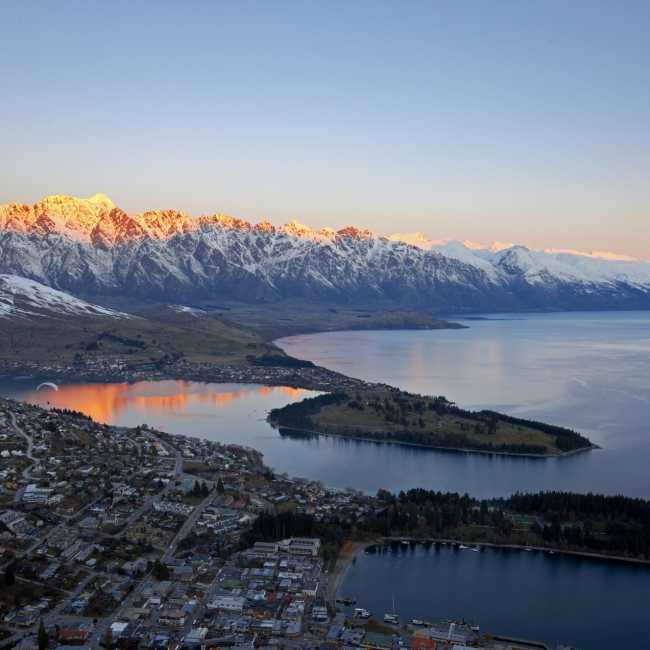 Aerial shot of Queenstown with snow capped mountains, lake and town