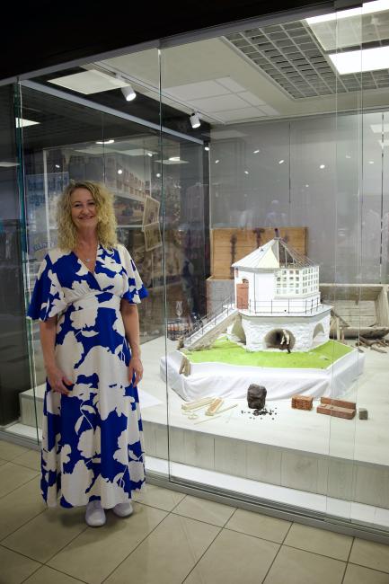 Kvinne står foran en utstillingsmontér med en modell av Markøy fyr og historiske elementer, i anledning fyrets 300-årsjubileum.
