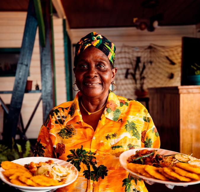 Afro-Caribbean woman serving traditional Caribbean dishes on Bastimentos Island, Panama.