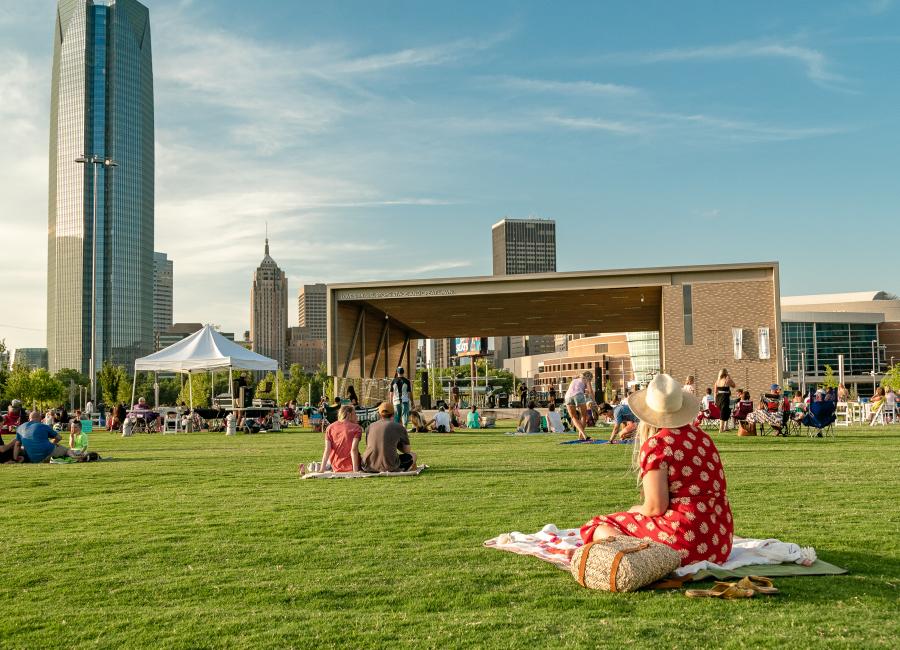 Photo of girl on blanket sitting in the lawn at Scissortail Park