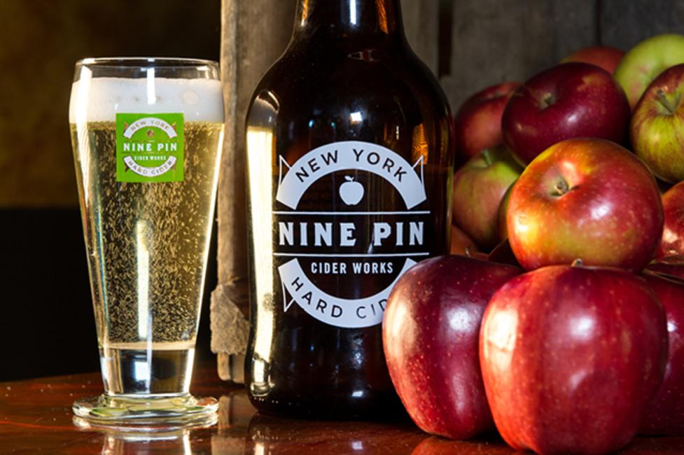 Nine Pin Cider Works A photo of cider in a Nine Pin Coder Works glass next to some red apples