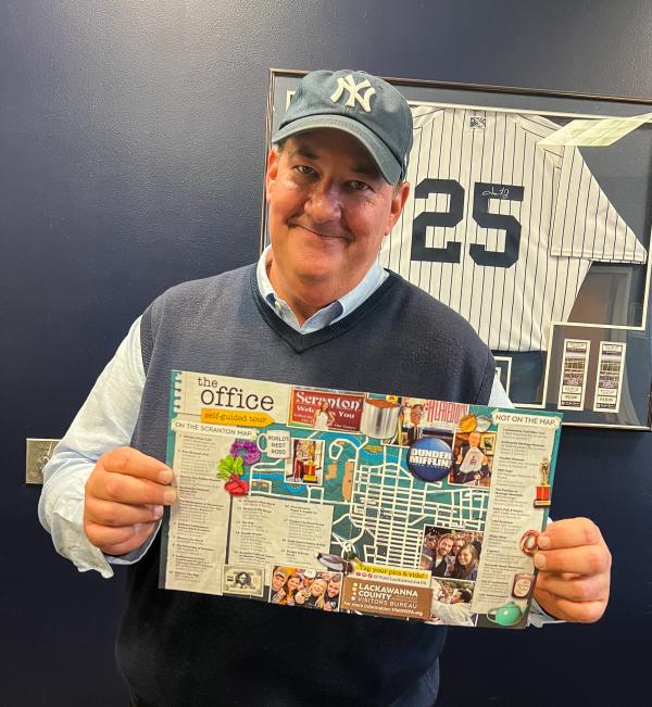 Brian Baumgartner (aka Kevin from The Office tv show) holding The Office Self-Guided Tour map
