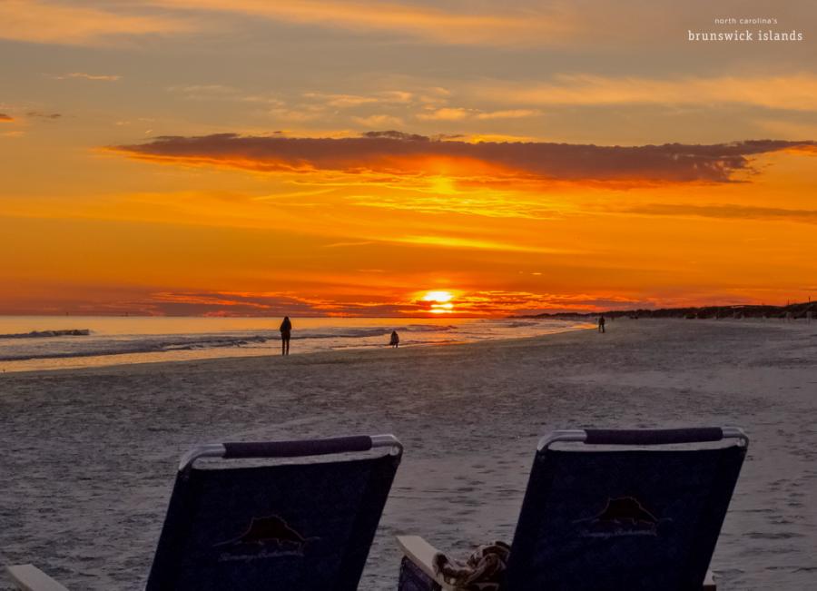 sunset over the ocean with two beach chairs in front