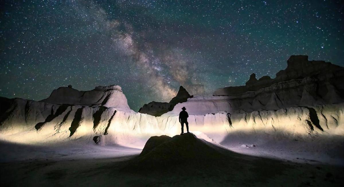 Star gazer standing in Badlands National Park at night
