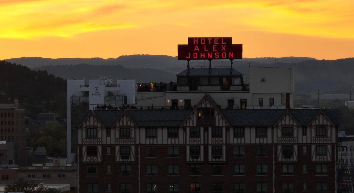 Hotel Alex Johnson sign in front of the sunsetting over the black hills in rapid city south dakota