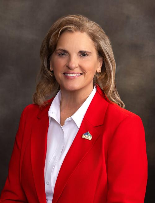 Headshot of smiling woman wearing a white shirt and red blazer