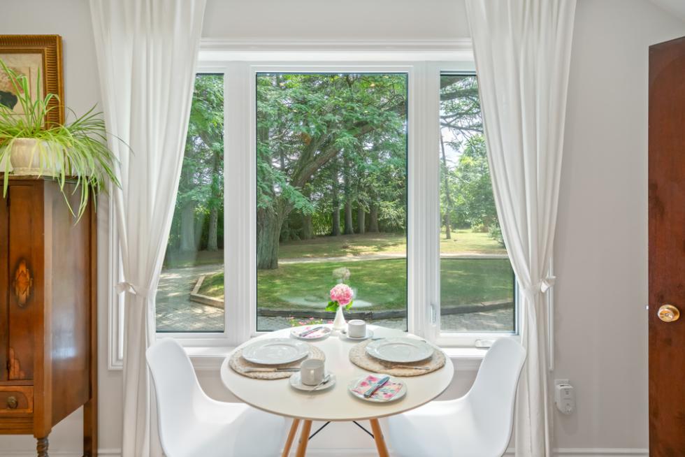Dining table in front of a window, with greenery in the background.