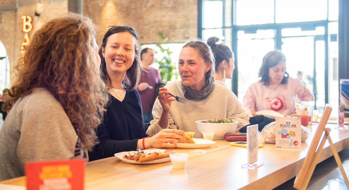 Three women share a laugh while enjoying Ian's Pizza at Garver Feed Mill