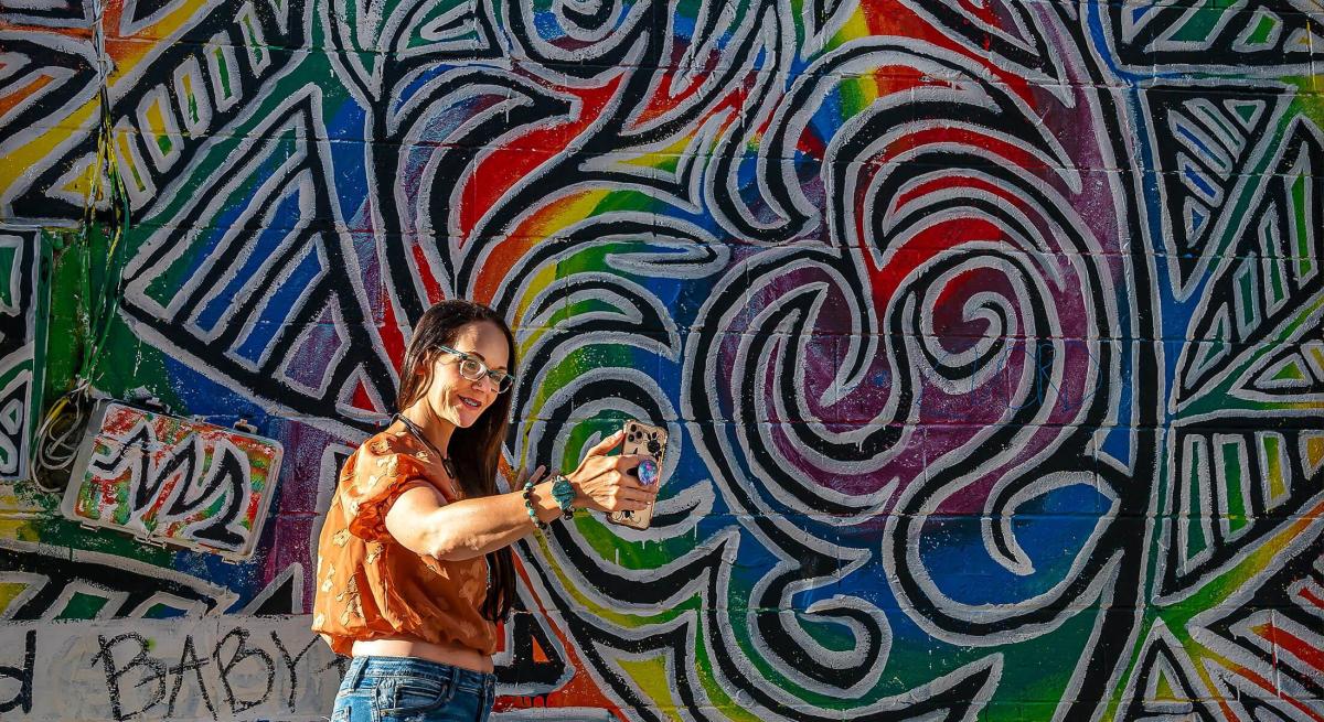 person taking a selfie in front of abstract heart mural in art alley in rapid city sd