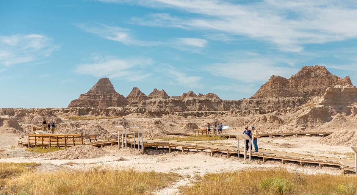 People on the boardwalk exploring parts of Badlands National park in the summertime