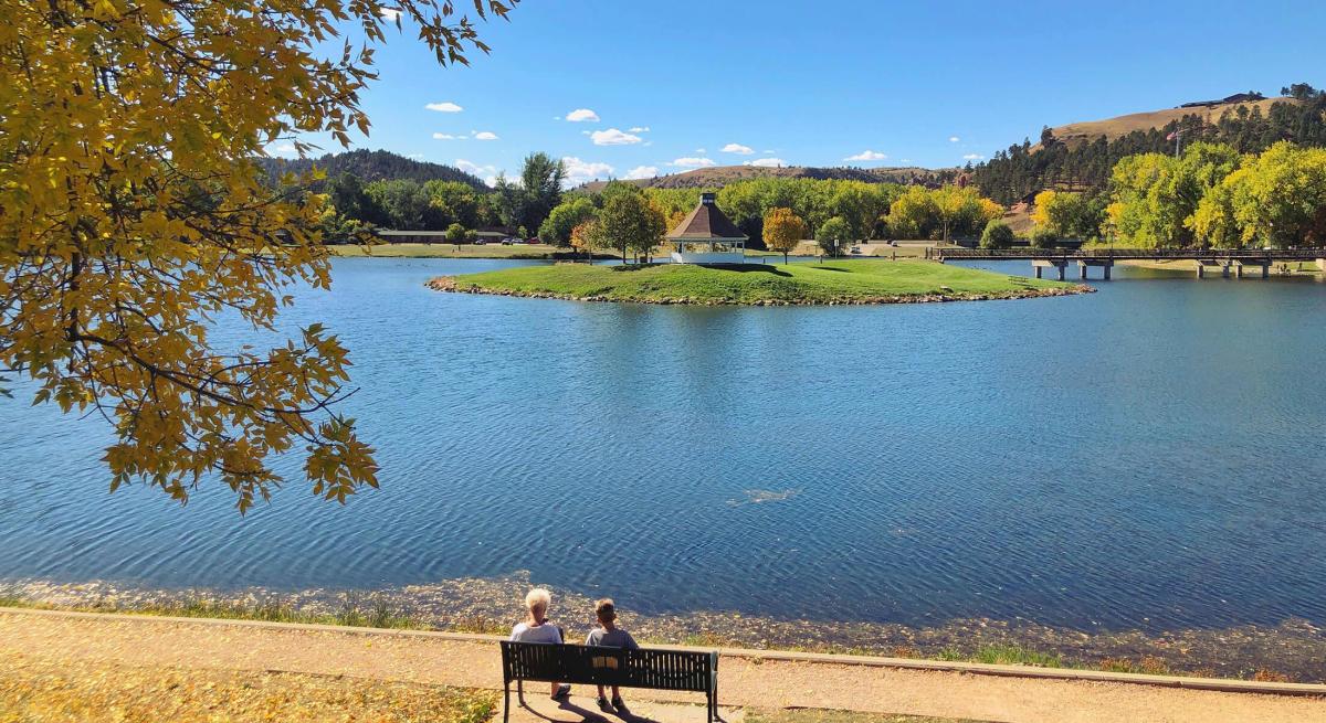 People sitting on bench looking out at Canyon Lake Park in Rapid City, SD