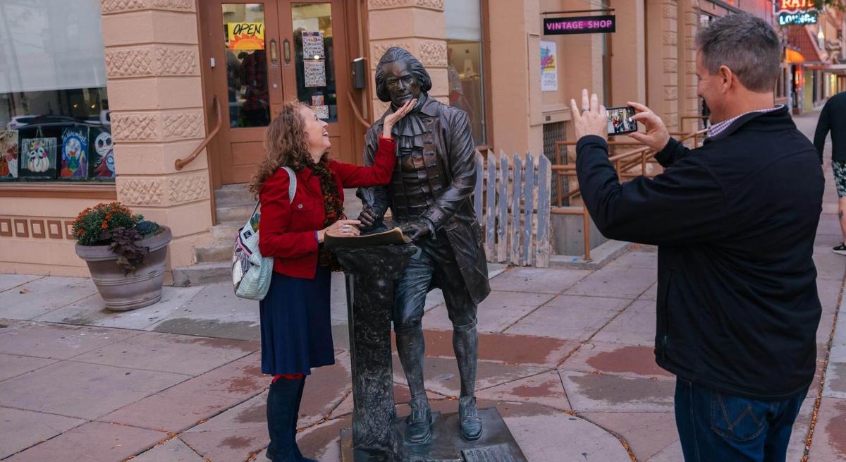 Couple posing with Thomas Jefferson's city of president statue in Rapid City, South Dakota