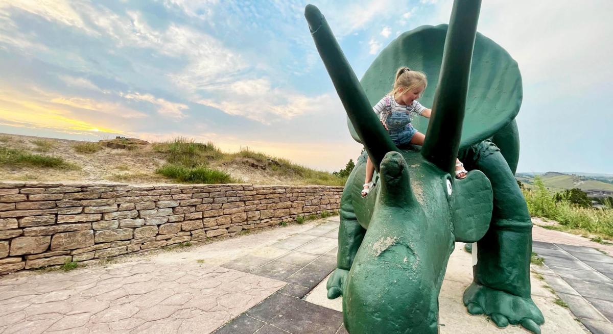 kid climbing on the Triceratops statue found at dinosaur park in rapid city south dakota
