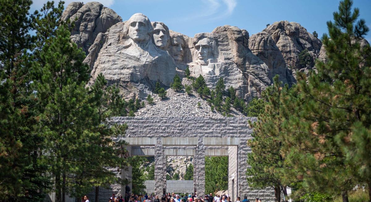 People walking through the memorial with Mount Rushmore in the background