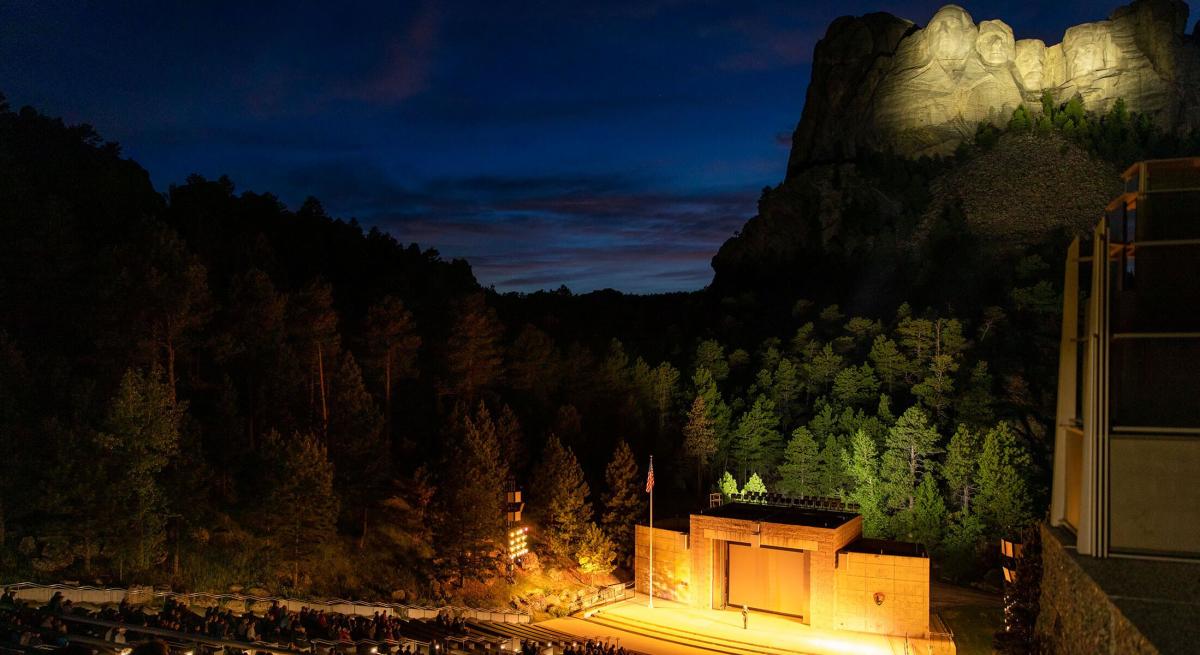 Evening lighting ceremony at Mount Rushmore with the stage and illuminated monument behind
