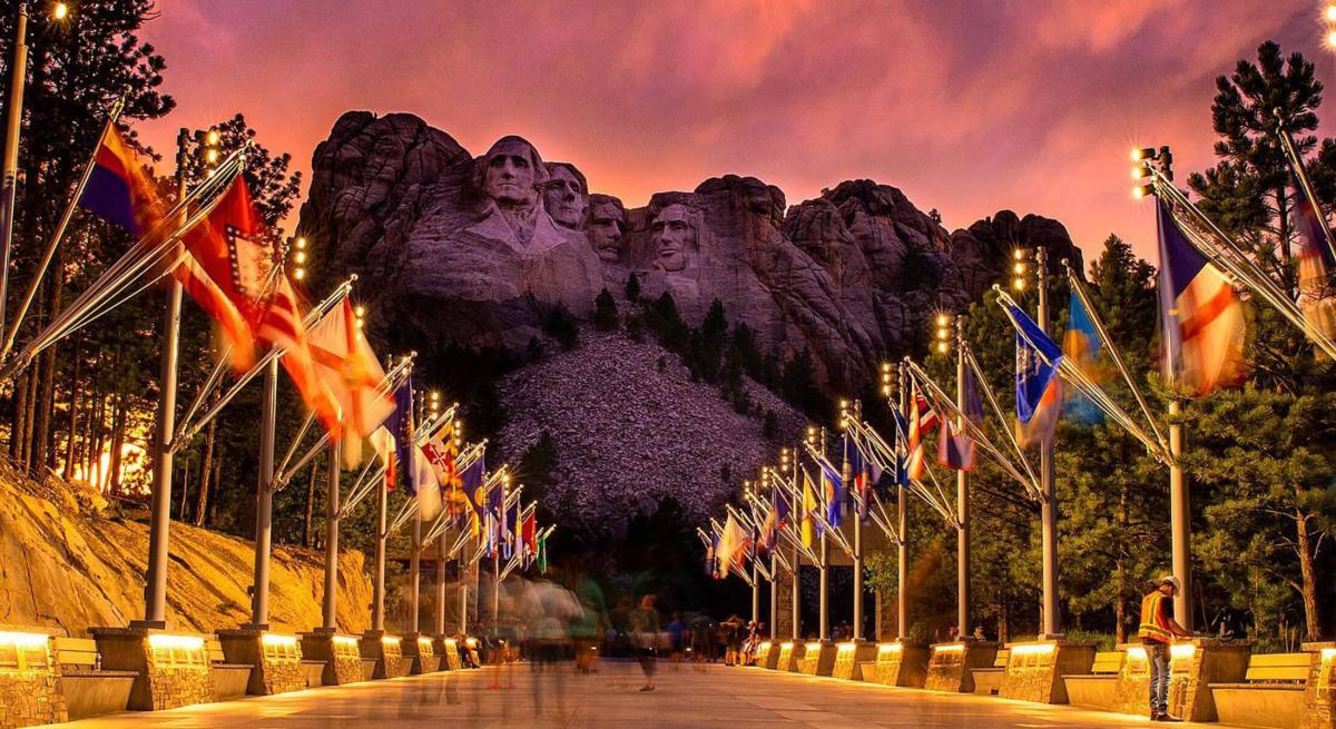 Sunset colors behind mount rushmore with the avenue of flags in front 